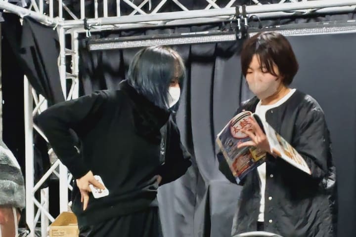 腰に手を当てた団員と雑誌を広げる団員が向き合う場面｜劇団カスタリア 演技稽古