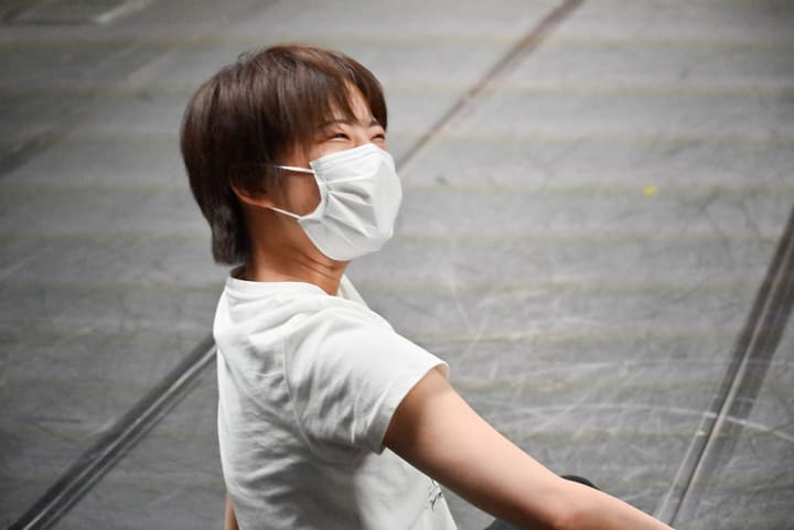 白いTシャツ姿で振り返り、目を細めて笑う団員｜劇団カスタリア 振付稽古