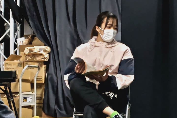 椅子に腰かけて雑誌をめくる場面を演じる団員｜劇団カスタリア 演技稽古