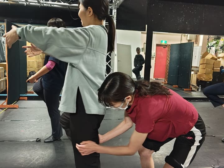 仲間に体を支えられながら前屈し、柔軟をする団員たち｜劇団カスタリア ダンス基礎練習