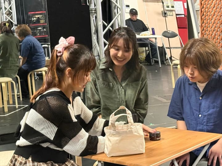 テーブルを囲んで差し入れを覗き込む出演者たち｜劇団カスタリア 稽古の合間