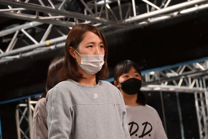 グレーのスウェット姿で正面を見据える団員と、後ろに並ぶ仲間たち|劇団カスタリア 二幕通し稽古