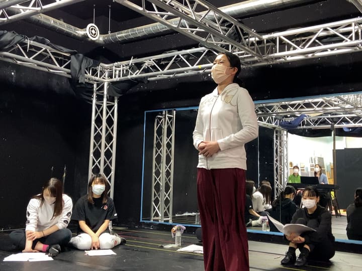 床に座る仲間の前に一人で立ち、声を出す団員｜劇団カスタリア「オーブ」発声練習