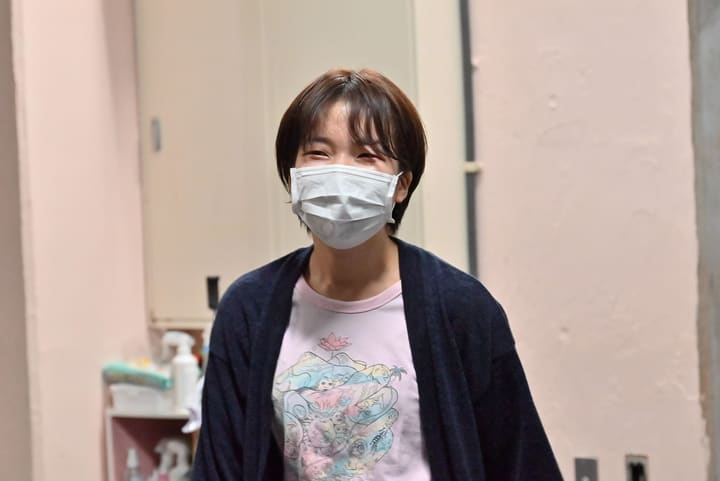 稽古場の壁を背に、こちらを向いて笑う団員｜劇団カスタリア 稽古オフショット