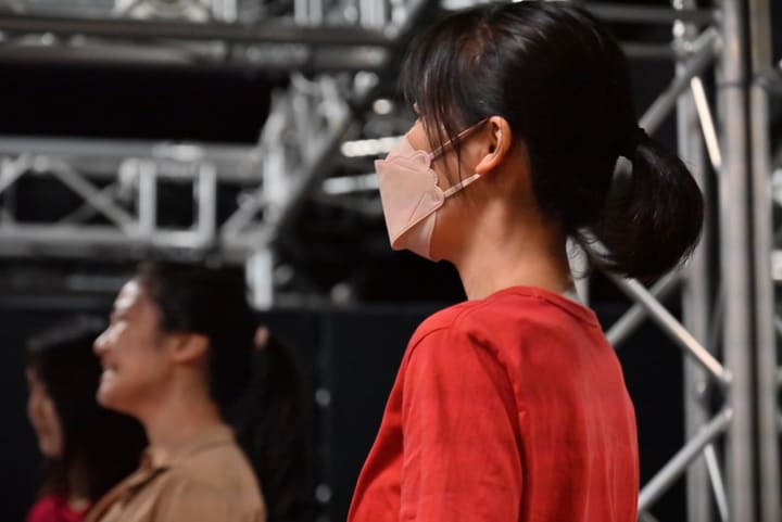 赤い服の出演者の横顔と、その奥で台詞を語るもう1人｜劇団カスタリア 通し稽古