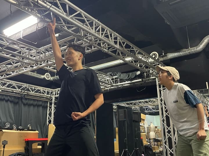人差し指を高く突き上げる男性団員と、隣で見つめる出演者｜劇団カスタリア「TRIP」稽古