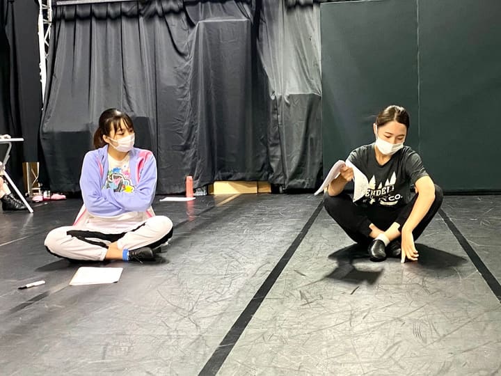 あぐらで座り、台本をめくって場面を確かめる団員2人｜劇団カスタリア 演技稽古