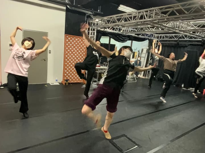 片脚を引き上げ、腕を頭上で構えて弾むように踊る団員たち｜劇団カスタリア ダンス稽古