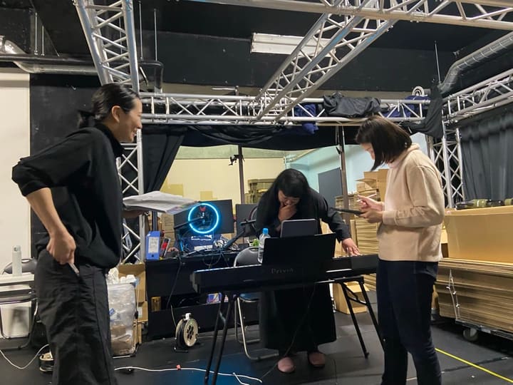 電子ピアノを囲み、譜面を確認しながら音を合わせる団員たち|劇団カスタリア 歌稽古
