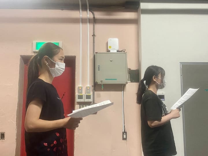 楽譜を手に、同じ方を向いて並んで歌う団員2人|劇団カスタリア 歌稽古