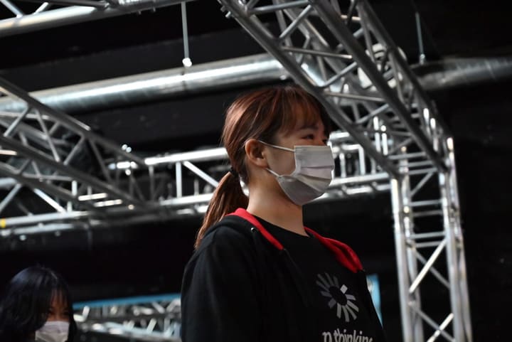 赤いフードの黒パーカー姿で、前方をまっすぐ見つめる団員の横顔｜劇団カスタリア ナンバー稽古
