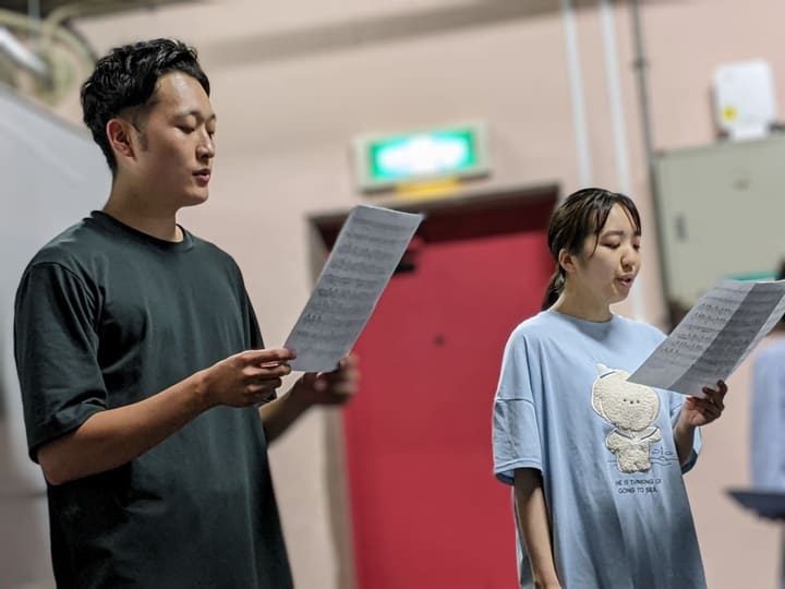 楽譜を手に持ち、並んで新しい楽曲を歌う団員2人|劇団カスタリア「TRIP」歌稽古