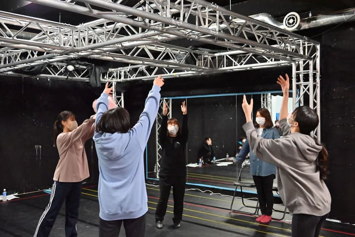 講師の前で全員が片手を高く上げ、新しい振りを覚える様子|劇団カスタリア 新曲の振り入れ