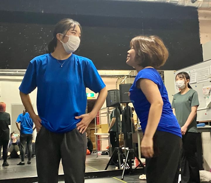 青いTシャツ姿の2人が腰に手を当てて向かい合う場面｜劇団カスタリア 通し稽古