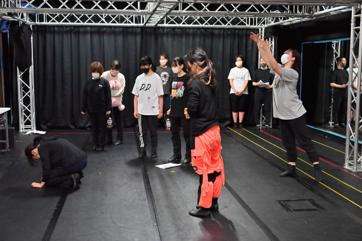 腕を高く挙げて動きを指示する団員と、ランタンを持って並ぶ出演者｜劇団カスタリア ステージング稽古