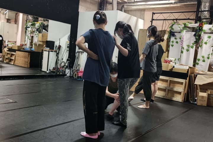 背中と脚に手を添えてもらい、立ち姿勢を直す団員｜劇団カスタリア ダンス基礎練習