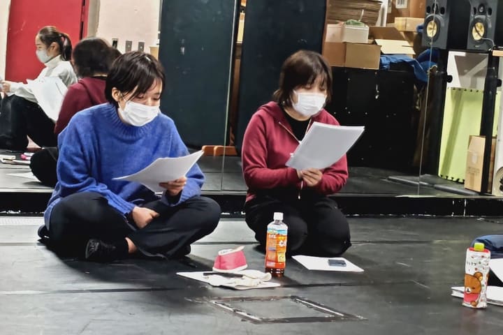 床に並んで座り、それぞれ台本に目を落とす団員2人｜劇団カスタリア 本読み稽古