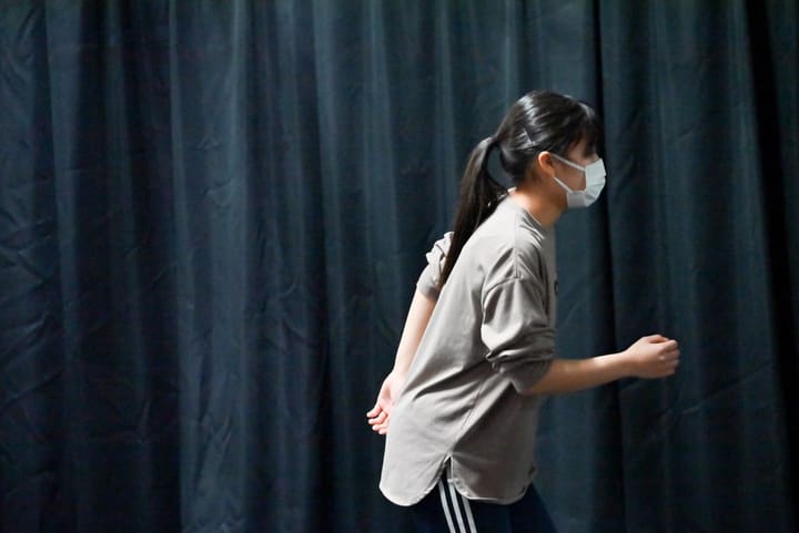 暗幕の前で身体を前に倒しながら歩く動きを確かめる団員|劇団カスタリア「オーブ」立ち稽古