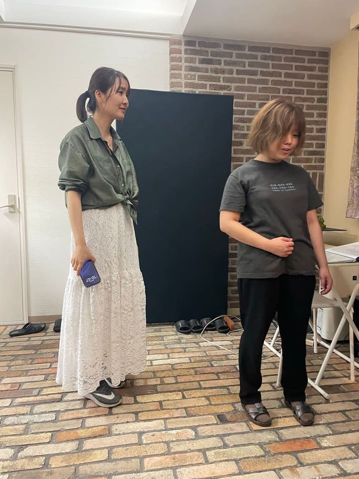 白い壁の部屋で向かい合い、稽古の合間に話す2人の出演者｜劇団カスタリア 稽古の合間