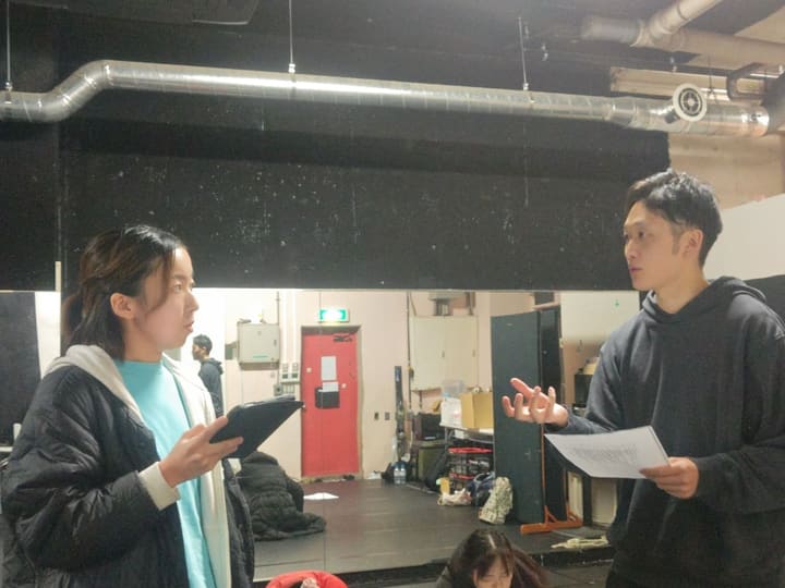 台本とタブレットを手に、間の取り方を話し合う団員2人｜劇団カスタリア 演技稽古