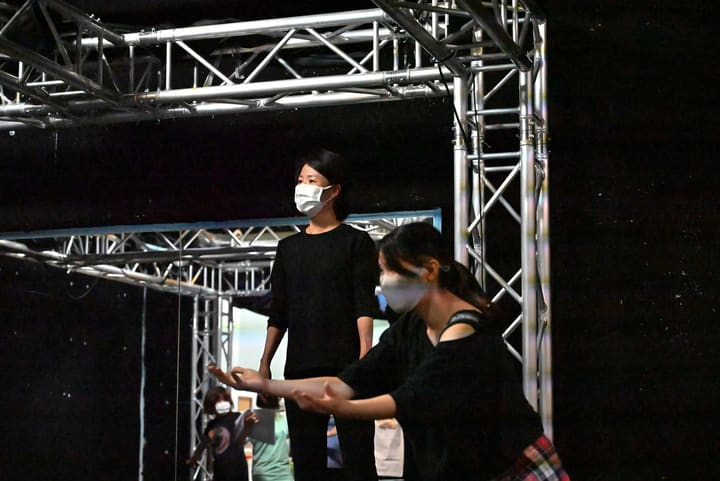 黒い服の団員の前で、両手を差し出して芝居をする出演者｜劇団カスタリア 立ち稽古