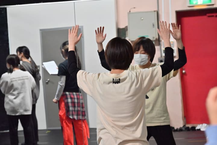 両手を高く上げて同じ振りの形をそろえる団員たち｜劇団カスタリア 振付稽古