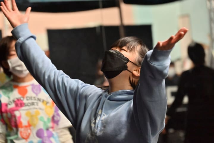 両腕を高く広げ、天井を仰ぐように踊る団員のアップ|劇団カスタリア ダンス稽古