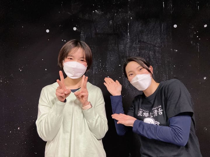 黒い壁を背にピースサインと手のひらでポーズをとる団員2人｜劇団カスタリア 稽古オフショット