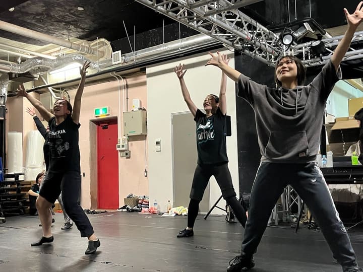 両腕を頭上へ大きく伸ばし、笑顔で踊る団員たち|劇団カスタリア ダンス稽古