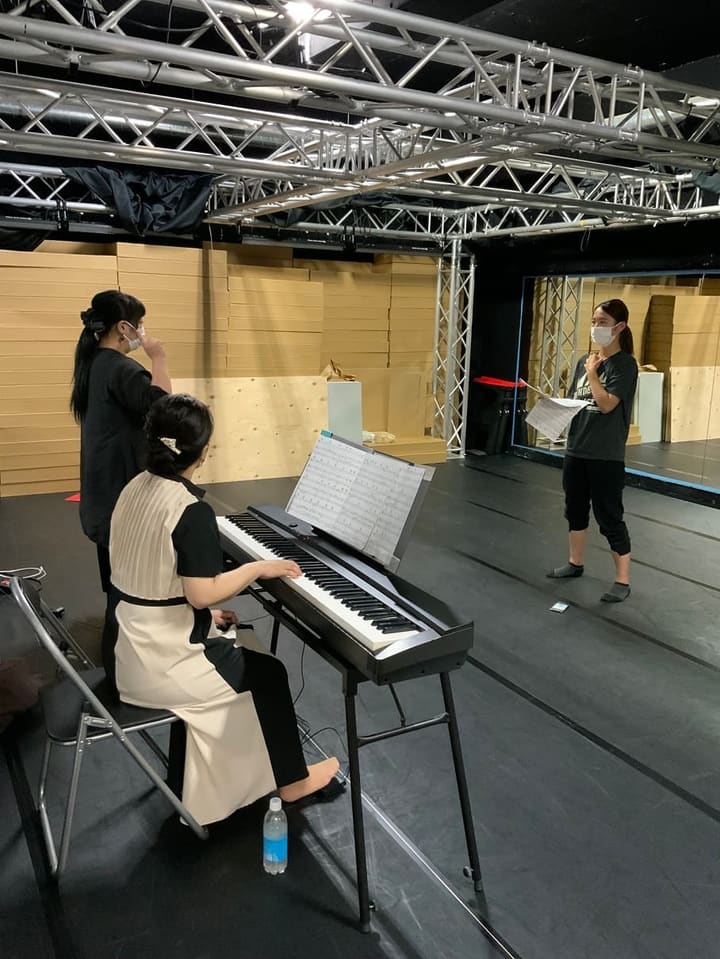 電子ピアノの伴奏に合わせ、譜面を手に歌う団員と講師｜劇団カスタリア 歌稽古