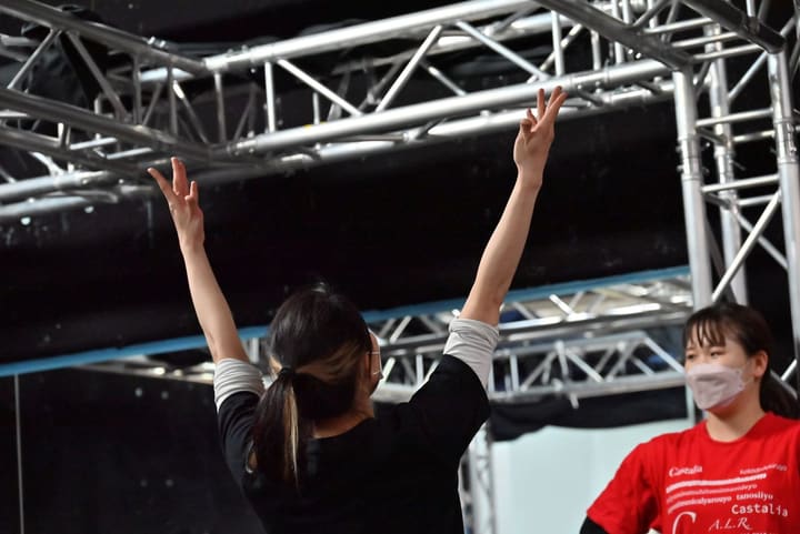 両腕を高く上げて指先まで伸ばす団員と、隣で見つめる仲間｜劇団カスタリア「オーブ」ダンス稽古
