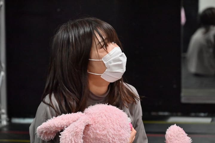 ピンクのぬいぐるみを胸に抱えたまま顔を上げて演じる団員|劇団カスタリア 二幕通し稽古