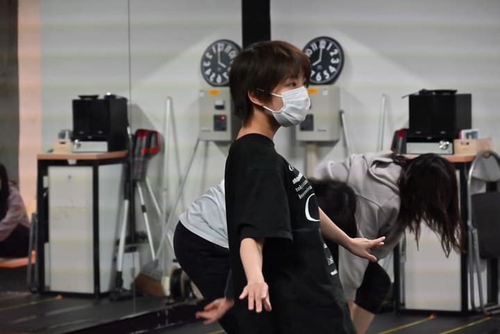 鏡張りの壁を背に、手を斜めに開いて振りの角度を確かめる団員｜劇団カスタリア ダンス稽古
