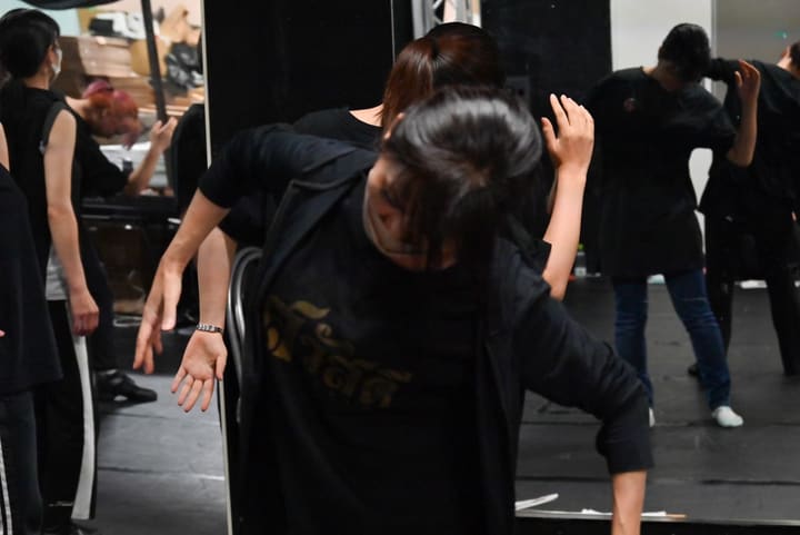 上体を大きく倒して腕を伸ばし、鏡の前で踊る団員たち|劇団カスタリア「ルドベキアフェスティバル」ダンス稽古