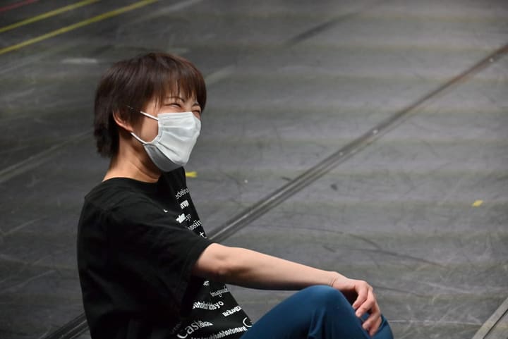 劇団名入りのTシャツで床に座り、笑いながら稽古を見る団員｜劇団カスタリア 稽古オフショット