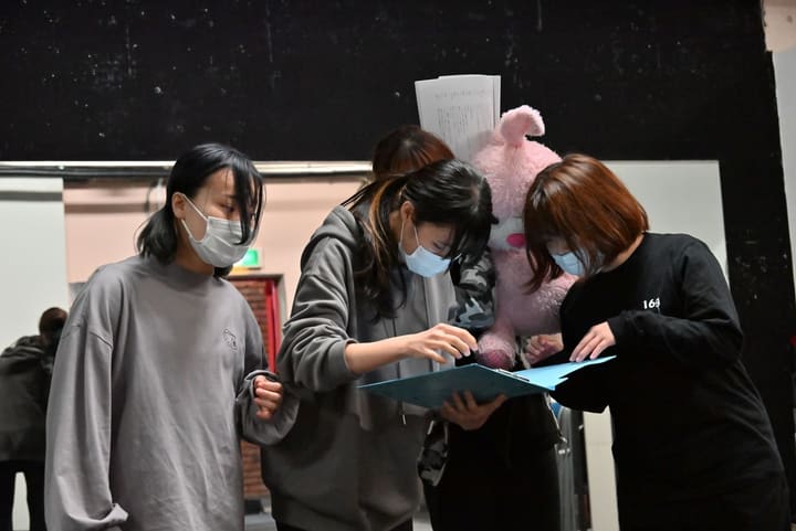 青いファイルを一緒に覗き込み、段取りを確認する4人の団員｜劇団カスタリア 一幕通し稽古
