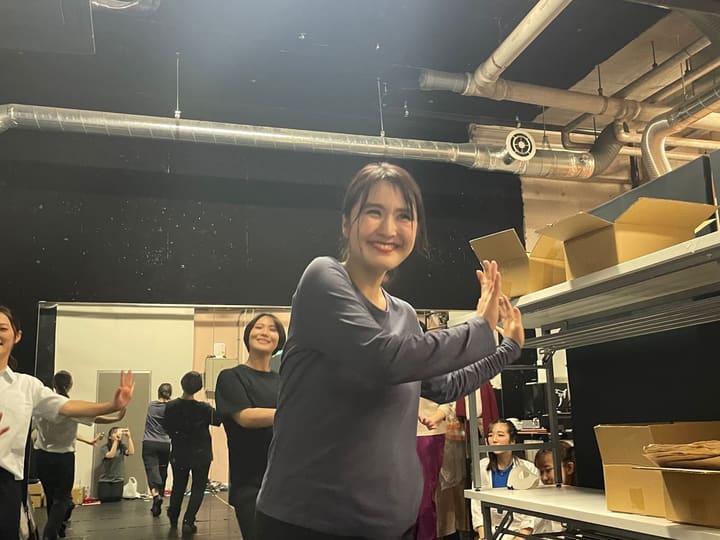 椅子に腰かけ、片手を上げて笑いながら演じる出演者|劇団カスタリア 通し稽古