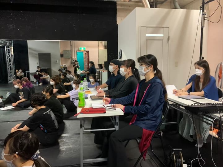 長机に着いて書き込む数人と、床に座って稽古を見つめる団員たち｜劇団カスタリア「オーブ」稽古