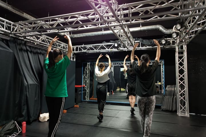 鏡に向かって並び、両腕を頭上に伸ばす団員4人｜劇団カスタリア ダンス基礎練習