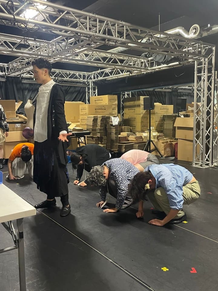 黒い長コートの出演者の前で、一斉に床へ身をかがめる一同｜劇団カスタリア「TRIP」通し稽古