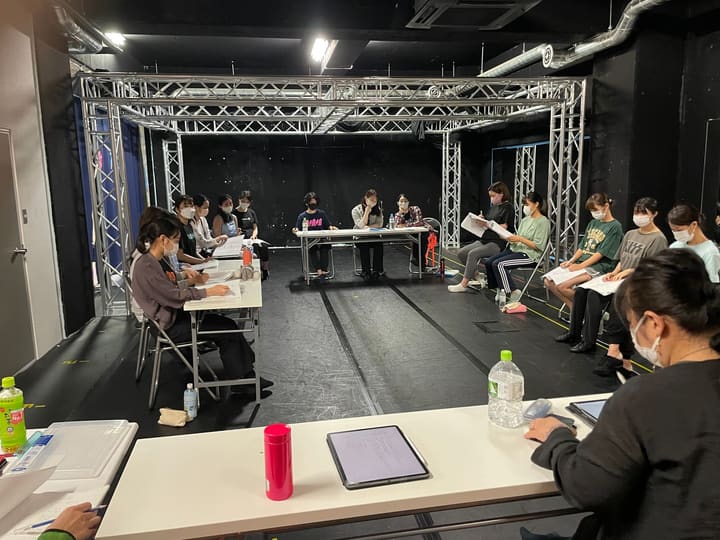 机を四方に囲んで座り、台本を開いて読み合わせる団員たち|劇団カスタリア 本読み稽古