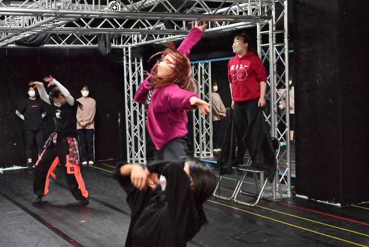 片腕を突き上げて踊る団員と、黒い布を垂らした台の上に立つ団員｜劇団カスタリア ダンスナンバー稽古
