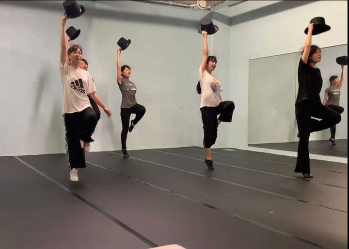 シルクハットを高く掲げ、片脚を上げて回る振りを踊る団員たち｜劇団カスタリア「DAHLIA」ダンス稽古