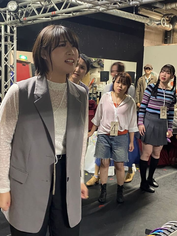 番号札を下げた仲間を背に、前へ出て台詞を言う出演者｜劇団カスタリア「TRIP」通し稽古