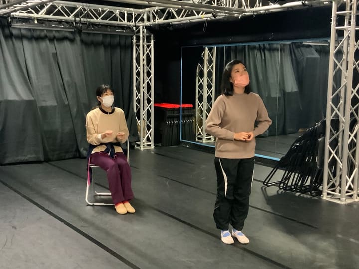 椅子に座る団員と立つ団員が、視線を上げて歌い出しを待つ｜劇団カスタリア 歌稽古