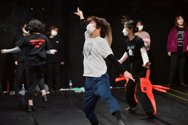 人差し指を天井へ伸ばし、上体を反らせて踊る団員と後ろに並ぶ仲間｜劇団カスタリア ダンスナンバー稽古