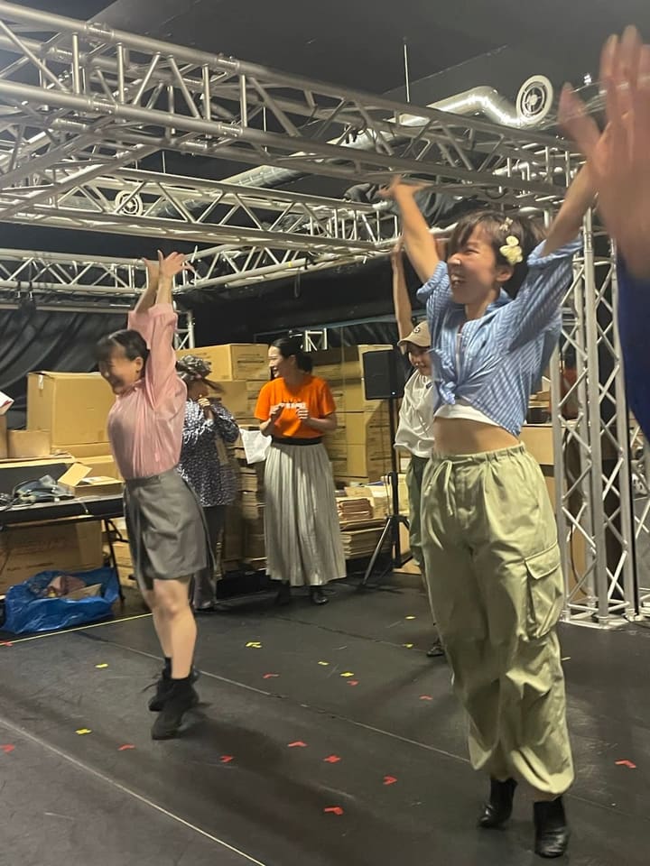両腕を高く上げて笑顔で踊る団員と、見守る仲間たち｜劇団カスタリア「TRIP」稽古場