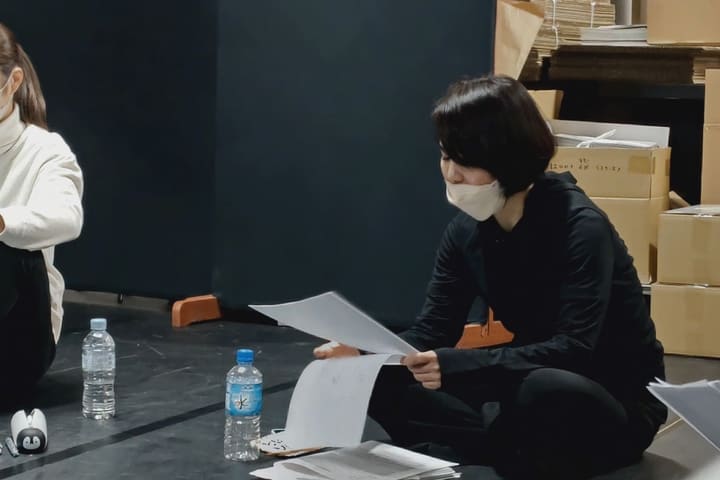 黒い稽古着で床に座り、めくった台本を読み込む団員｜劇団カスタリア 本読み稽古