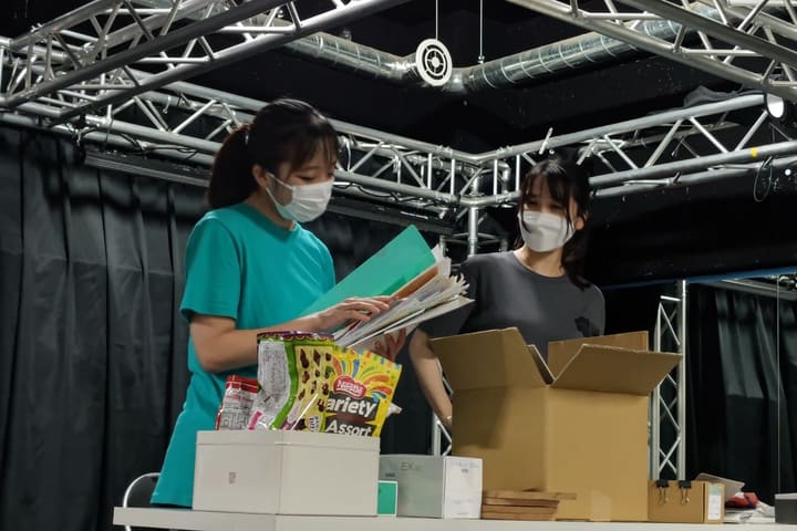 机の前で書類の束を抱え、顔を見合わせる出演者2人｜劇団カスタリア 二人芝居の稽古