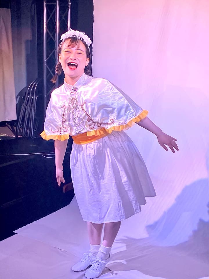 白い衣裳に花冠をつけ、口を大きく開けて笑う出演者|劇団カスタリア「オーブ」